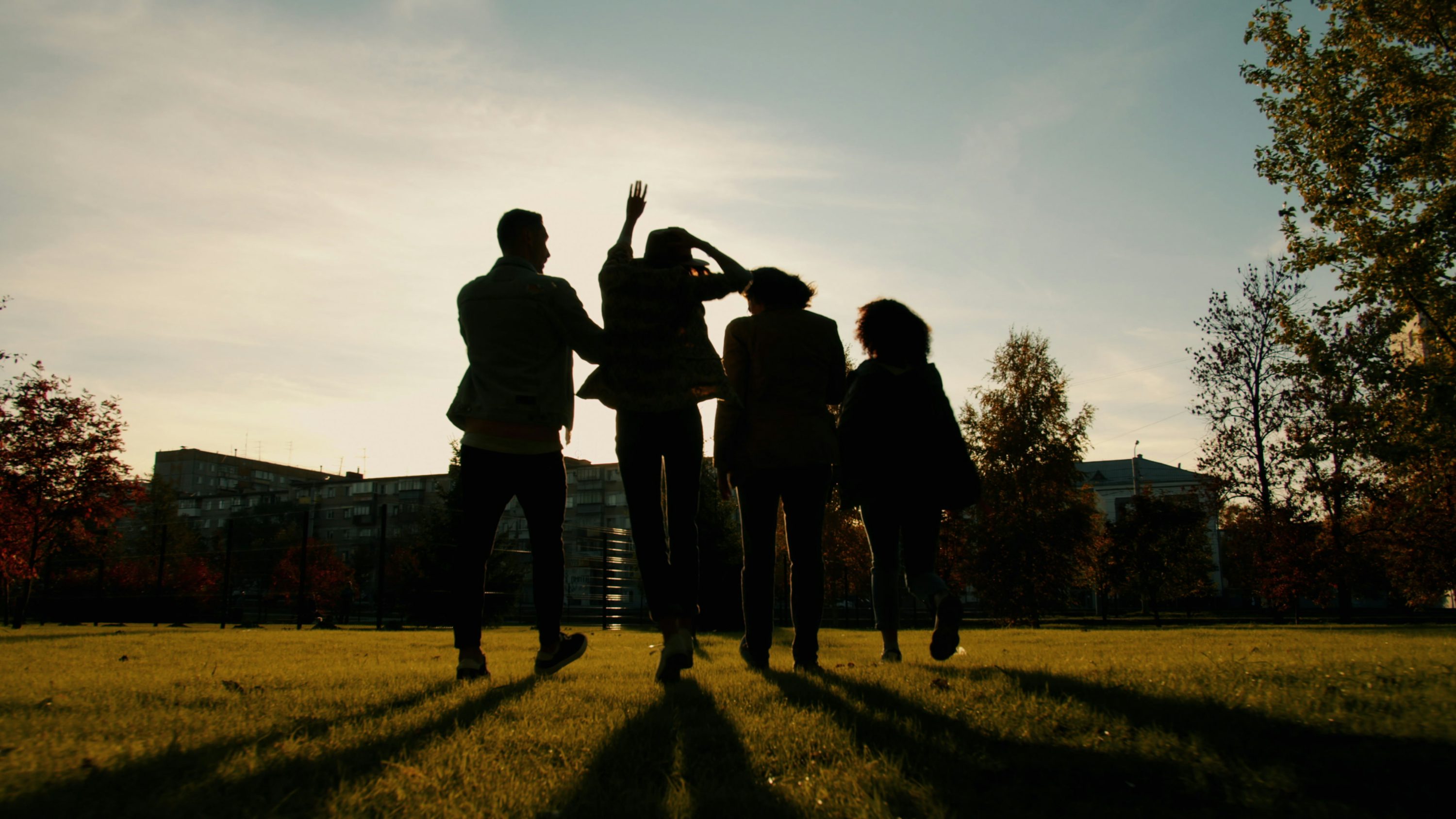 Four friends standing arm in arm on a hillside, watching the sun go down